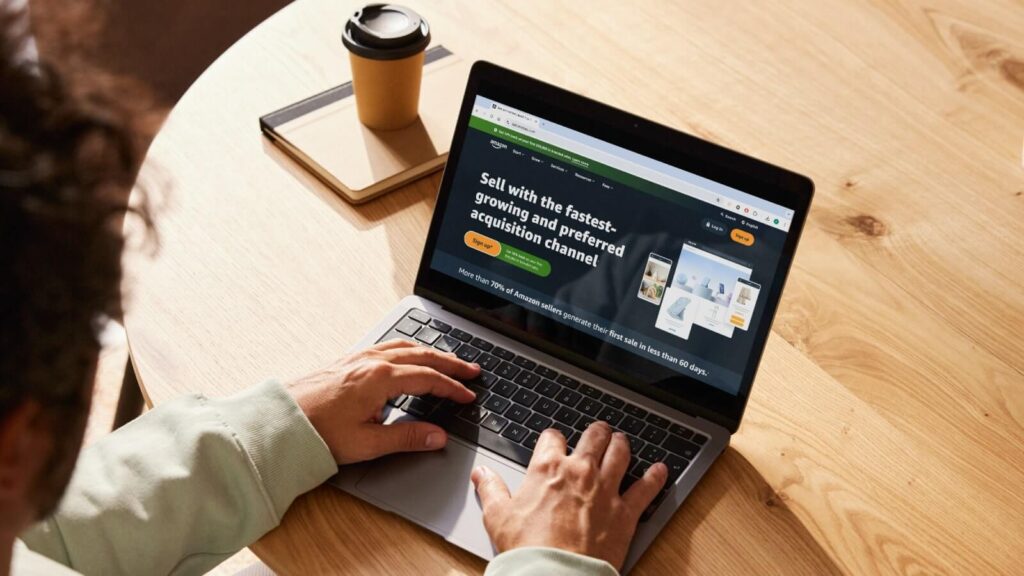 How to sell on Amazon Create an Amazon seller account A man sitting at a desk and viewing Amazon’s homepage on his laptop.