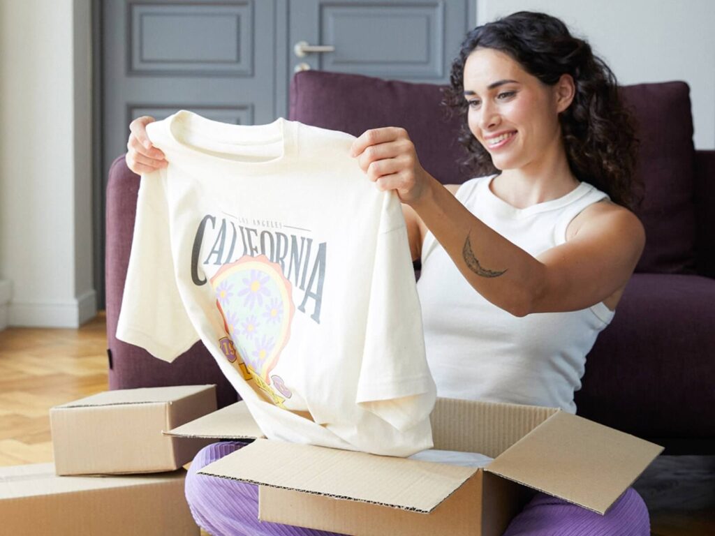 How to sell on Amazon Dropshipping A woman looking at a t-shirt she just unpacked.