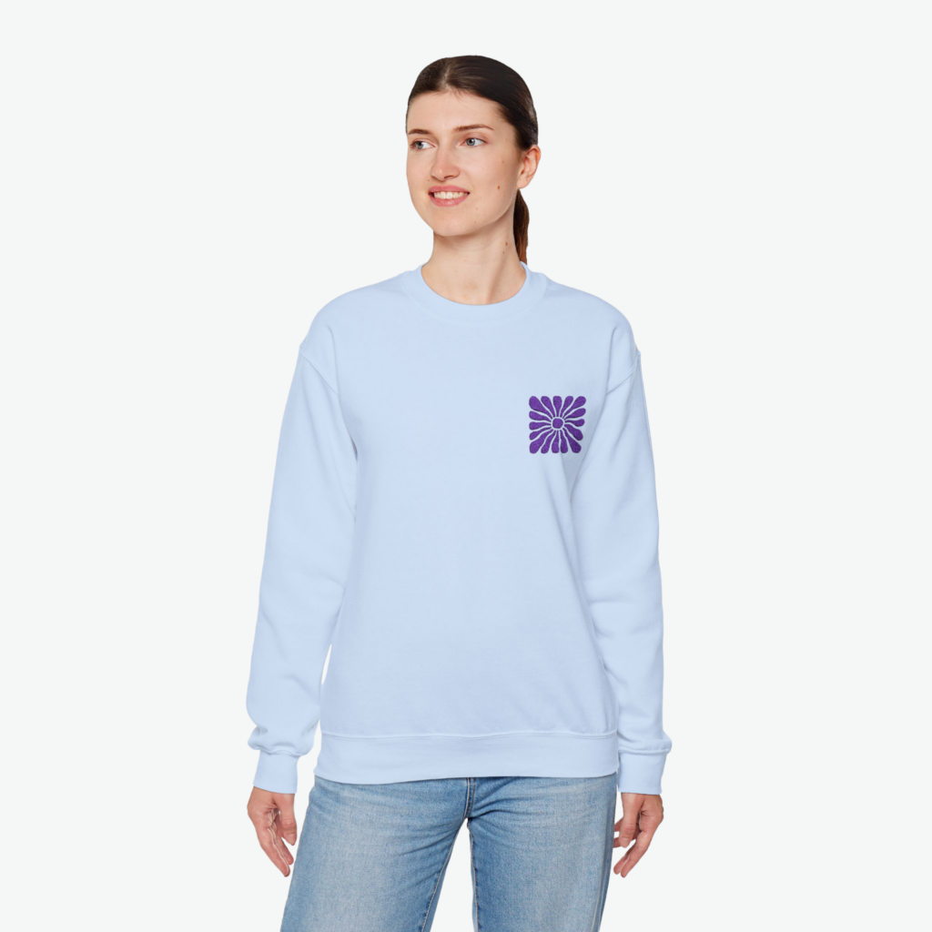 Botanical and floral embroidery A woman wearing a light blue hoodie with a small abstract shape print against a white background.