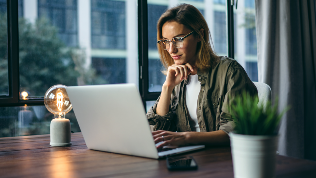 Learn and Adjust A woman sitting in front of a laptop at the table.