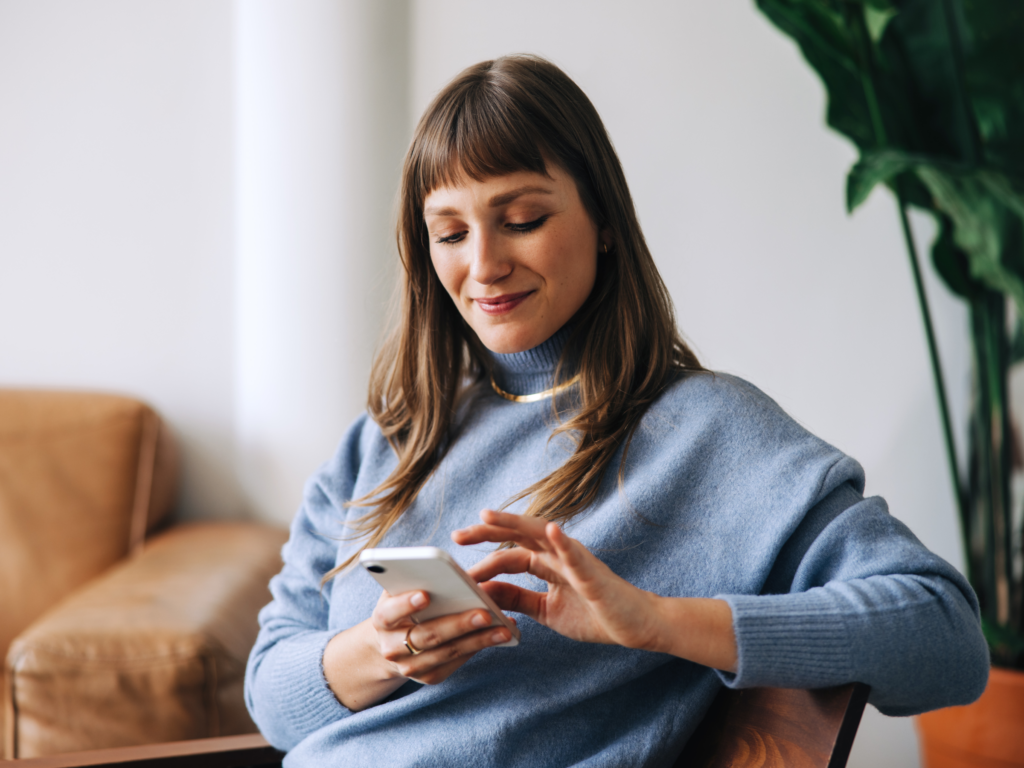 Engage with your target audience A woman sits comfortably on a chair, scrolling through her phone.