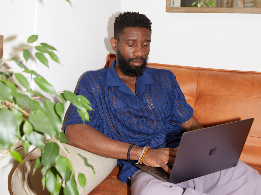Optimize your store A man sits on a couch with a laptop, focused on optimizing his online store.