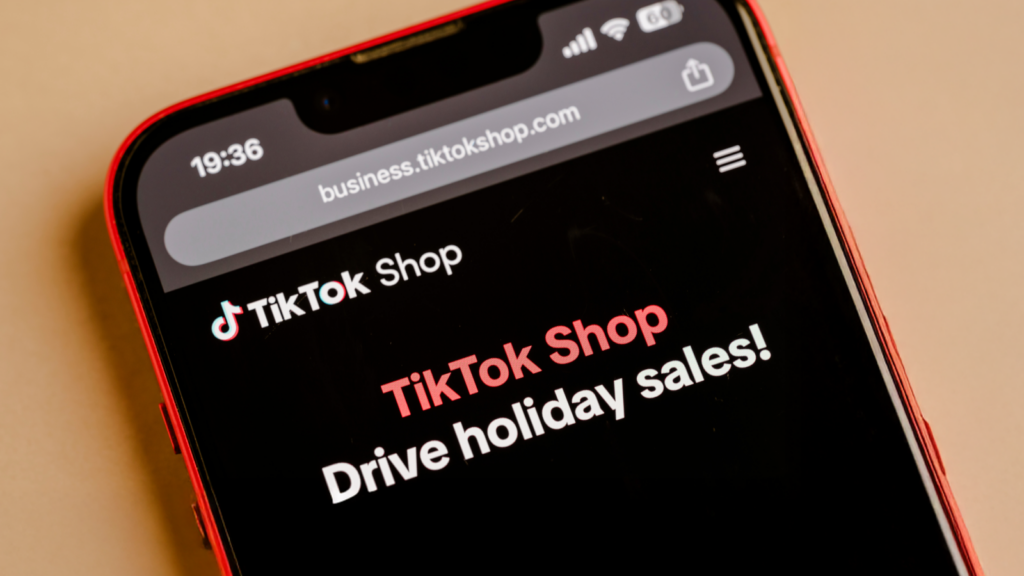 Set up your TikTok Shop or connect to Shopify Close-up of a smartphone screen displaying the TikTok Shop website with the message "Drive holiday sales!".