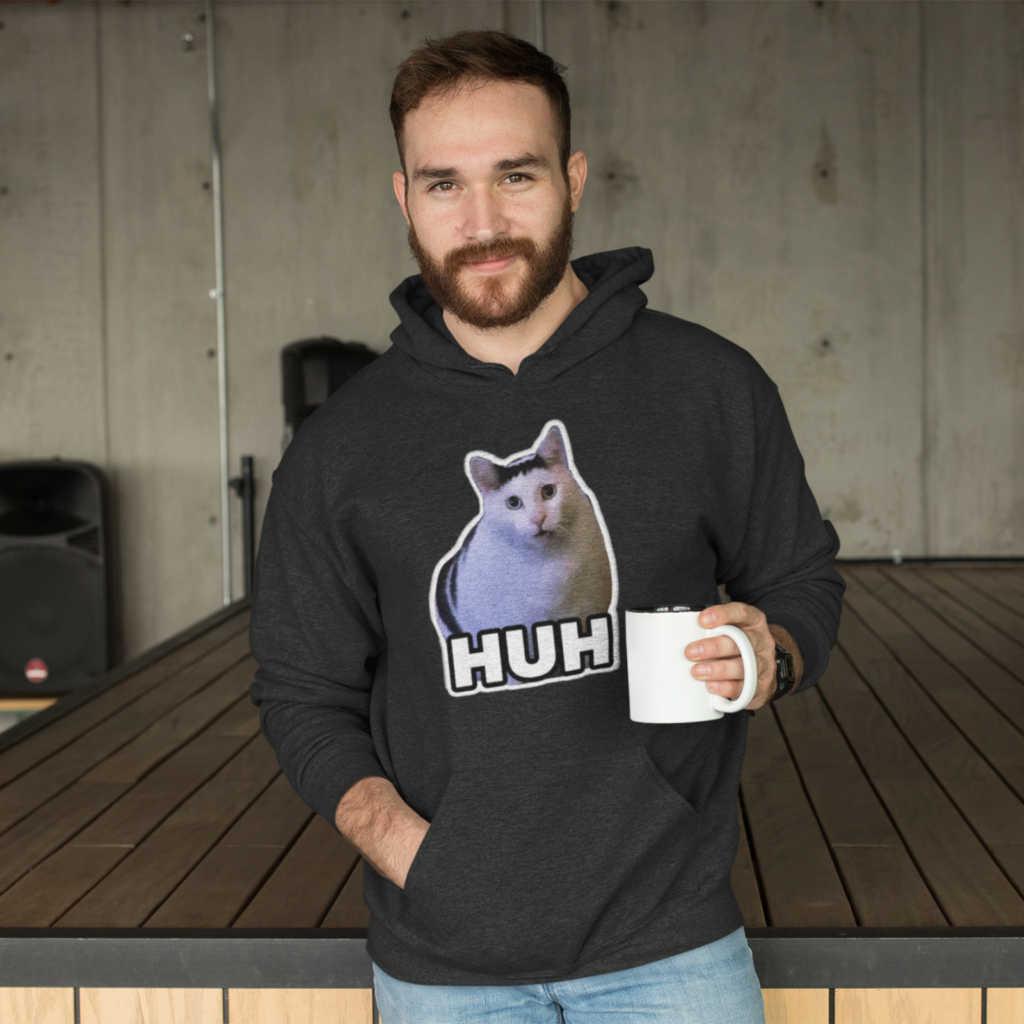 Trending memes A man wearing a trending hoodie with a cat meme print saying “Huh”.