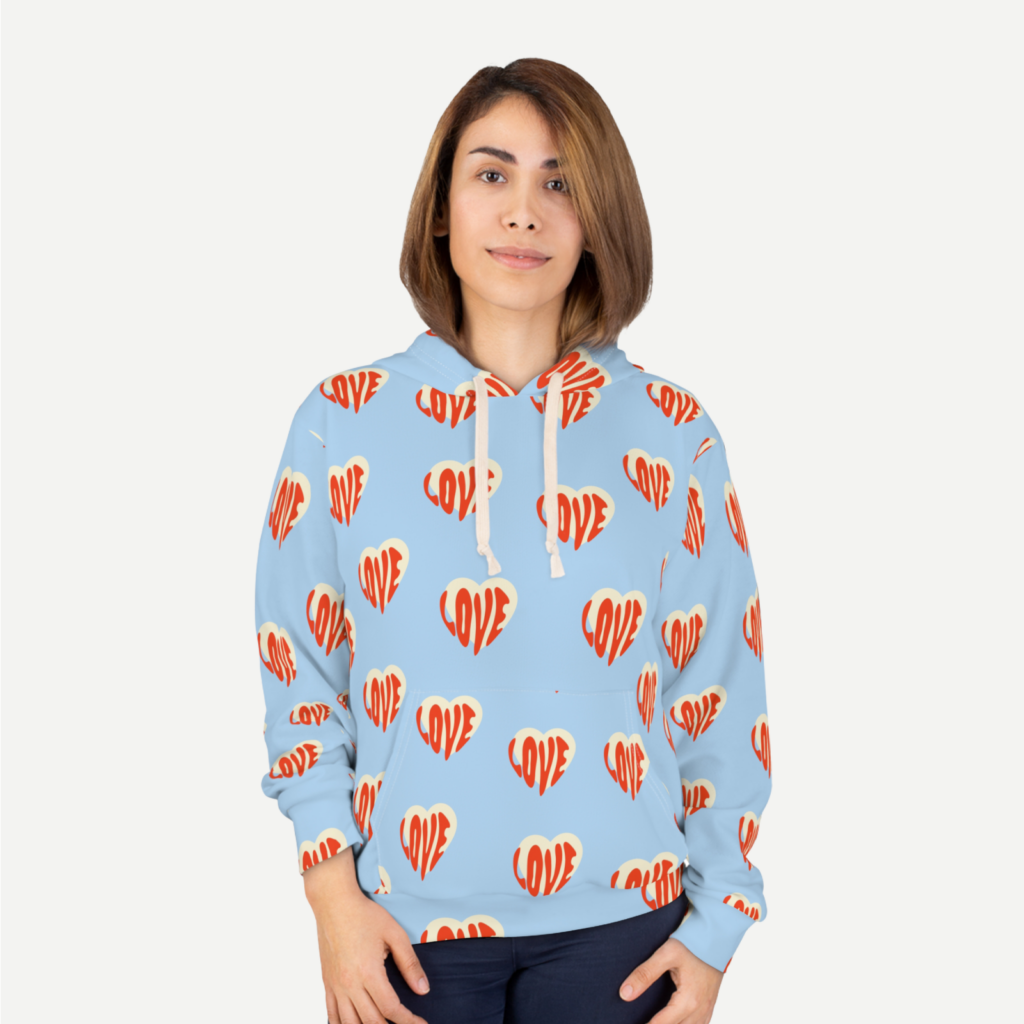 Unisex pullover hoodie AOP Generic brand A woman in a light blue hoodie with heart-shaped prints all over against a white background.